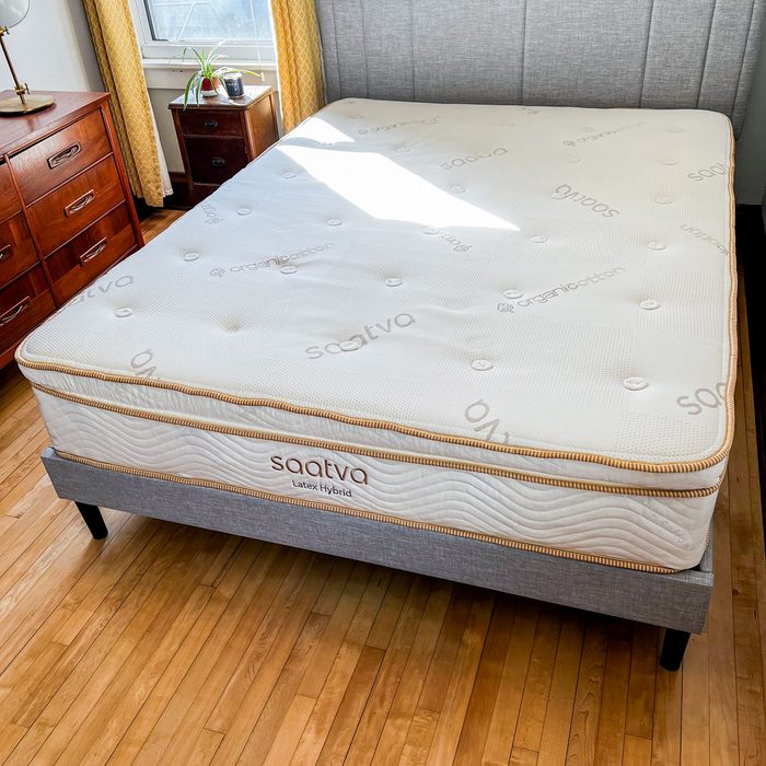 Mattress rests on a bed frame in a sunlit bedroom, with 