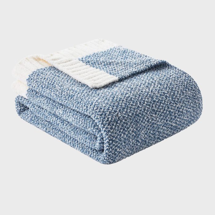A folded, textured blue and white blanket rests against a plain, light background.