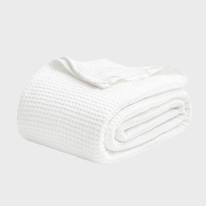 A folded white waffle-knit blanket on a neutral background.