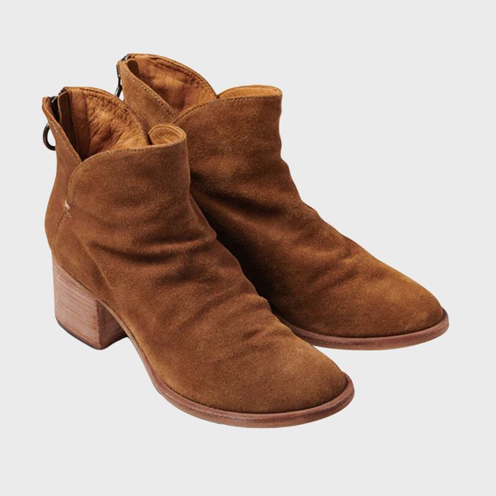Brown suede ankle boots are resting, with wooden block heels, on a plain light background.