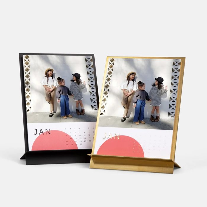 Two framed calendars display a photo of three people posing against a geometric wall, labeled 