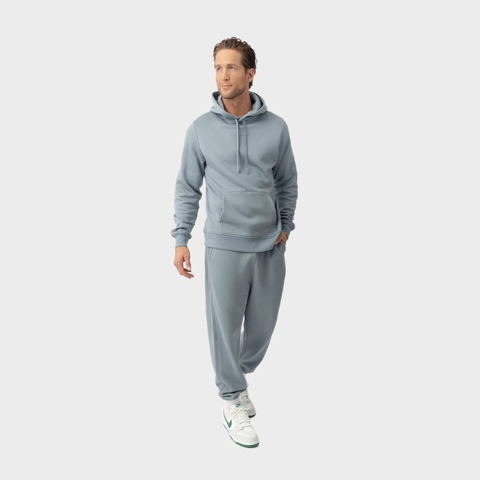 A person wearing a matching light blue hoodie and sweatpants walks confidently against a plain white background.