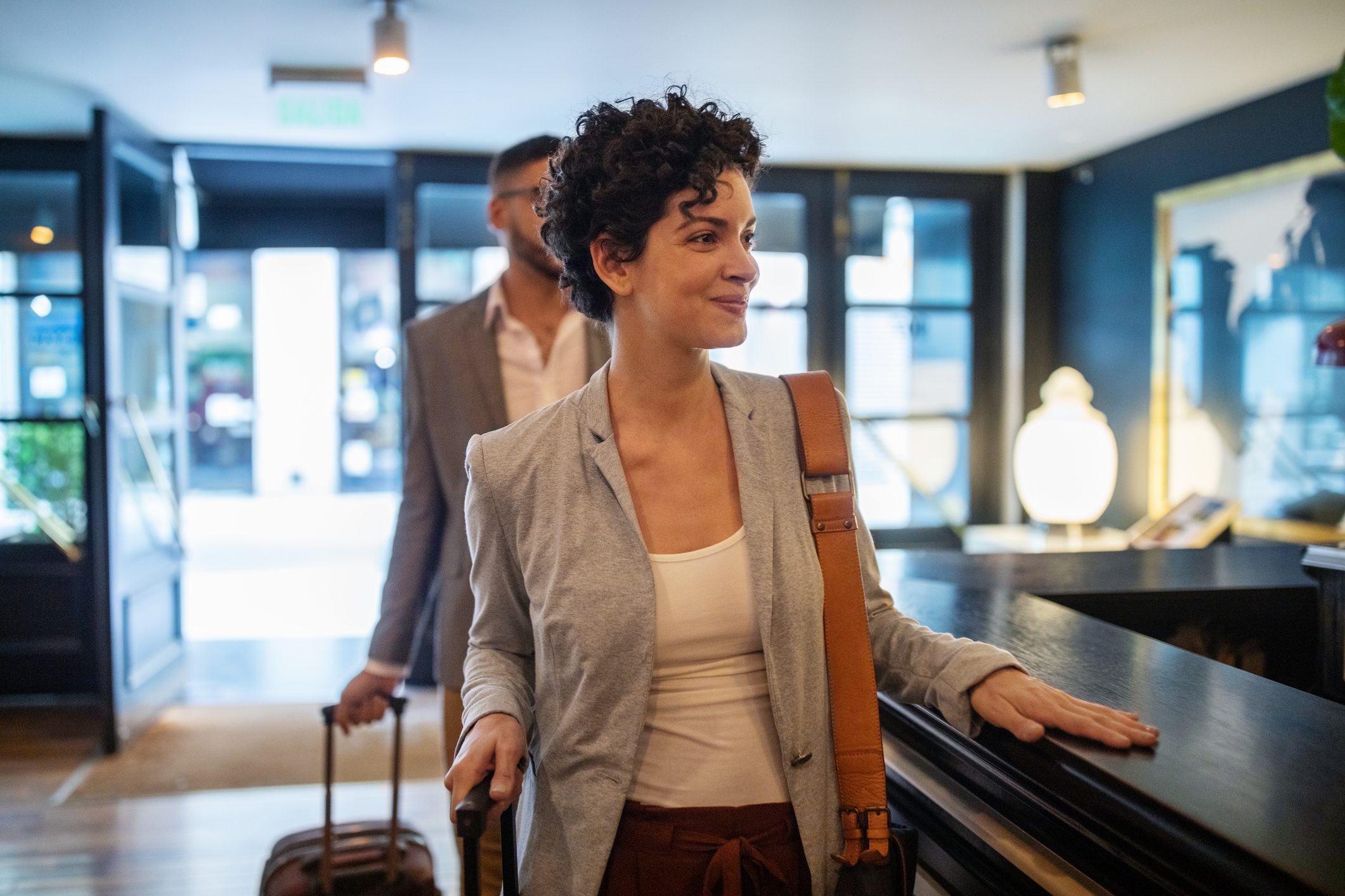 woman arriving in a hotel lobby with an anonymous man close behind her