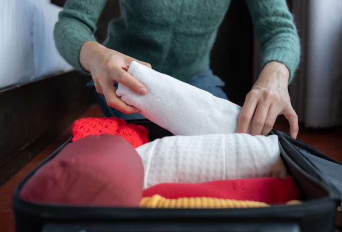 Close up of woman hands open suitcase and stealing hotel towel
