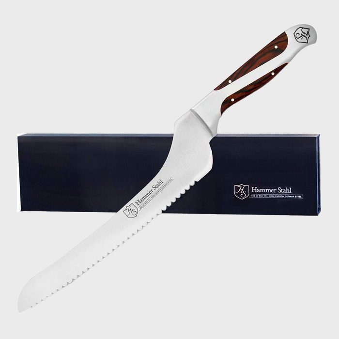 Knife rests on a box, featuring a serrated stainless steel blade and a wooden handle, with 
