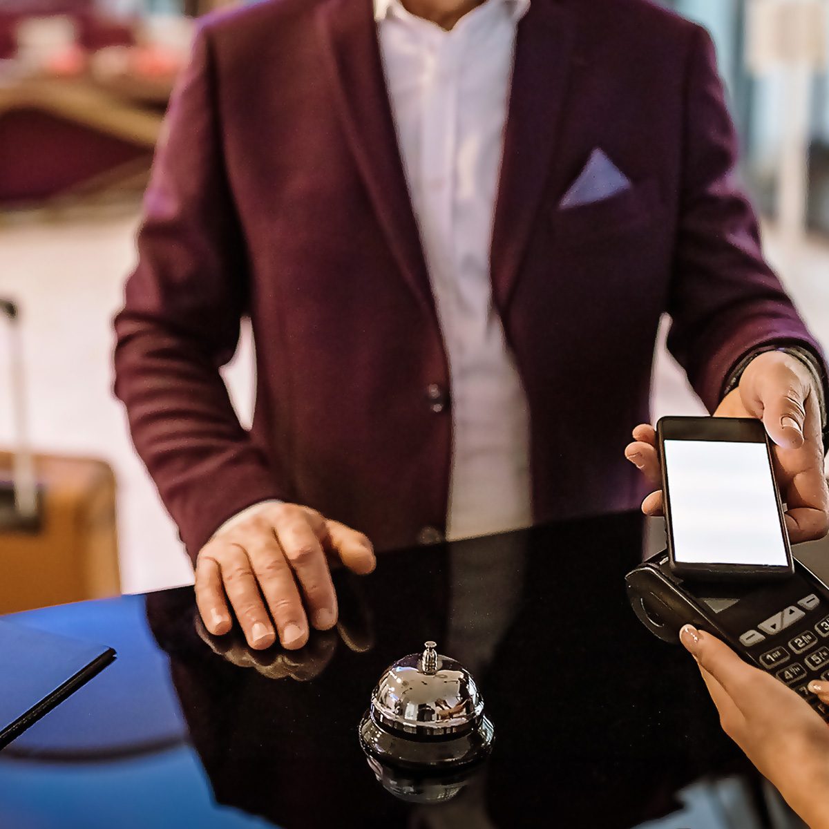 How Much To Tip In Every Situation man paying the hotel lobby receptionist via phone