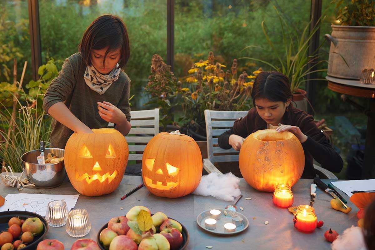 Children carve Jack-O-Lanterns for Halloween.