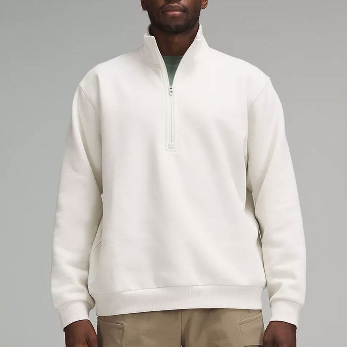 White quarter-zip sweater, worn by a person, standing against a plain gray background.