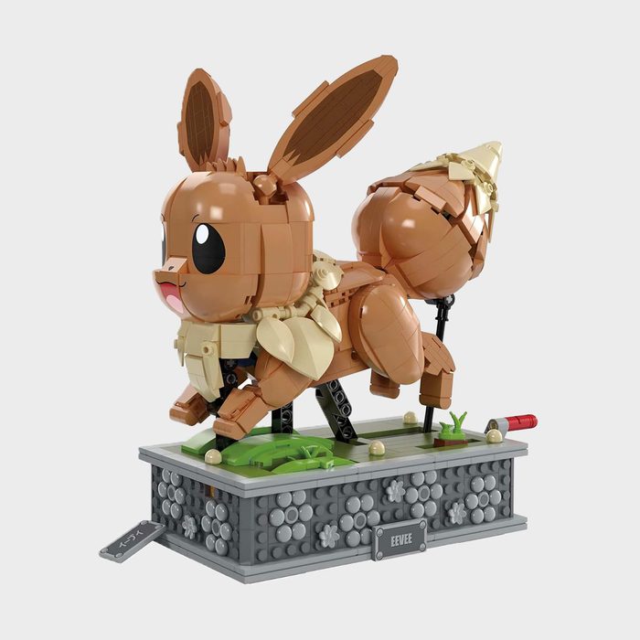 A LEGO Eevee model stands poised on a decorative base, surrounded by small plants and labeled plaques.