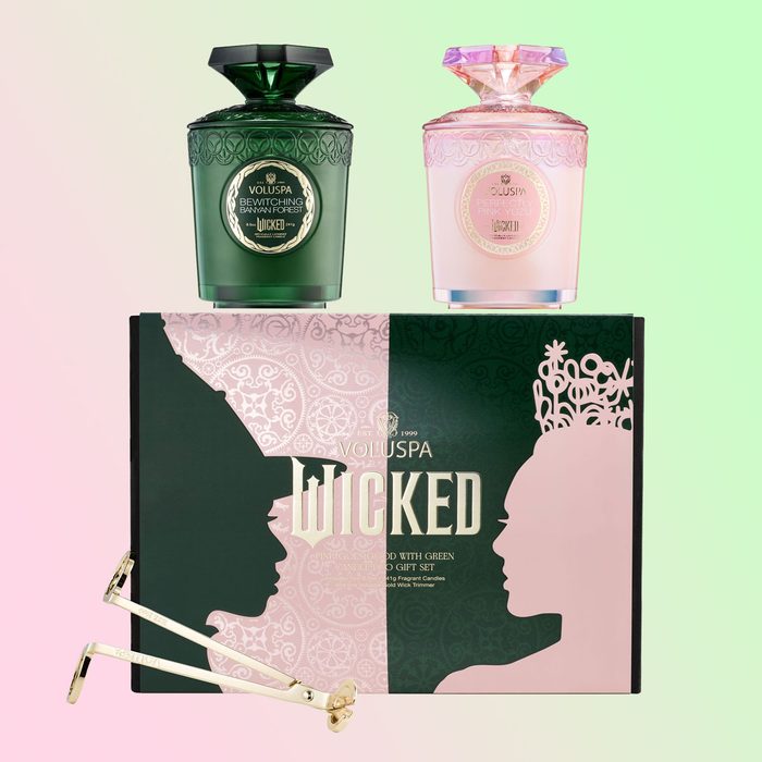 Candles rest atop a decorative box featuring silhouetted profiles. Gold wick trimmers lie nearby. Text: 