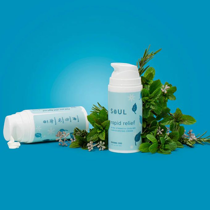Bottles stand and lie among green herbs on blue background; text reads 