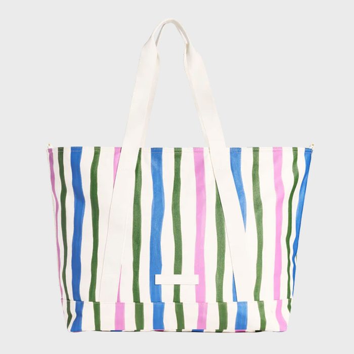 A large tote bag features vertical blue, green, and pink stripes with white handles, set against a plain background.
