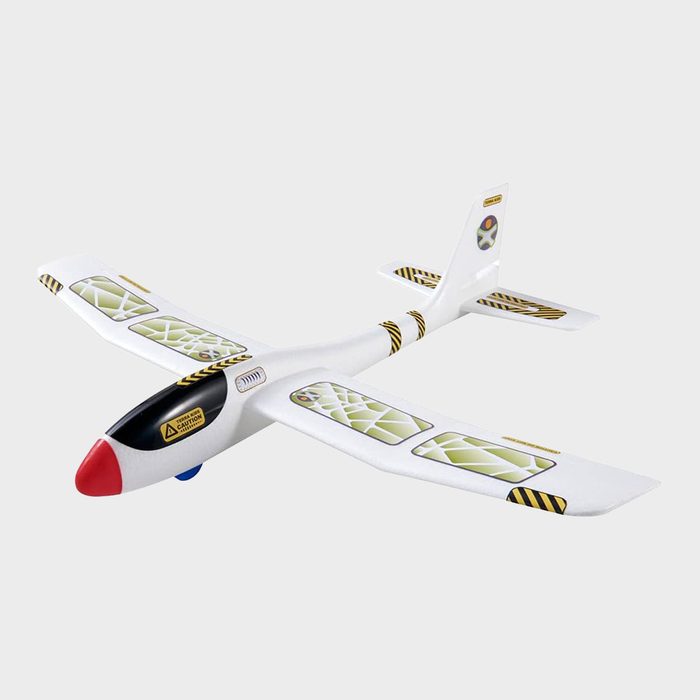 White toy glider with decals rests on a plain background, featuring a red nose and text 