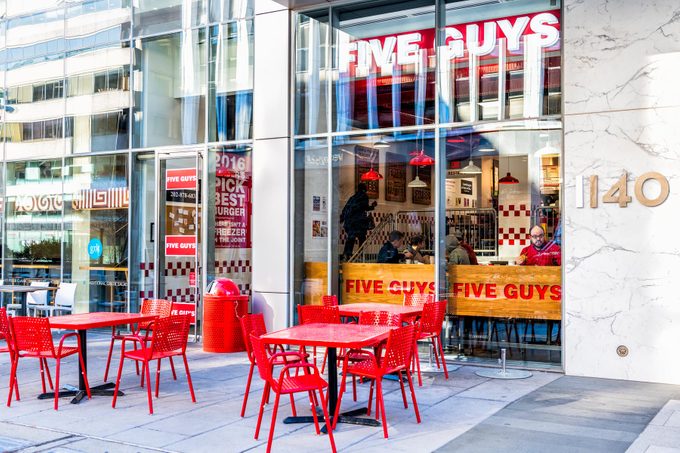 Five Guys restaurant, store burger chain entrance in District of Columbia with chairs, tables, outside, outdoor sitting area, people inside eating