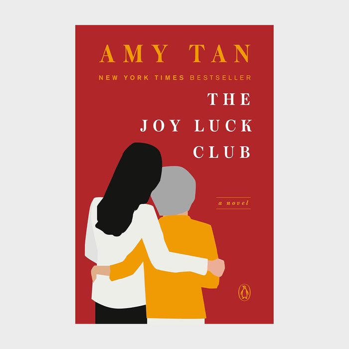 Two people embrace against a red background. Text reads: â€œAMY TAN, NEW YORK TIMES BESTSELLER, THE JOY LUCK CLUB, a novel.â€