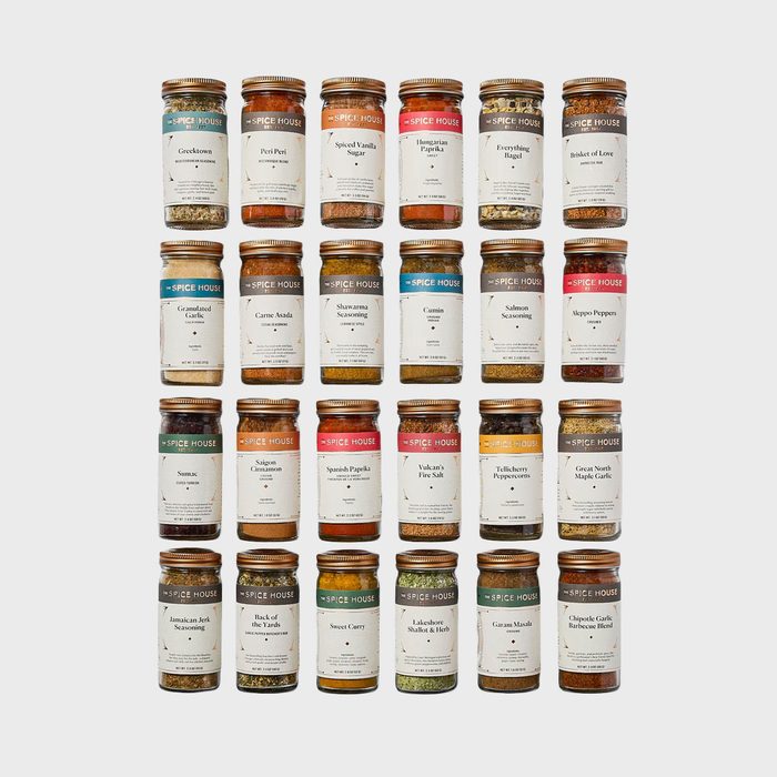 Jars arranged in a grid, containing various spices with labels, against a plain background. Each jar has a different name and type of spice mix.