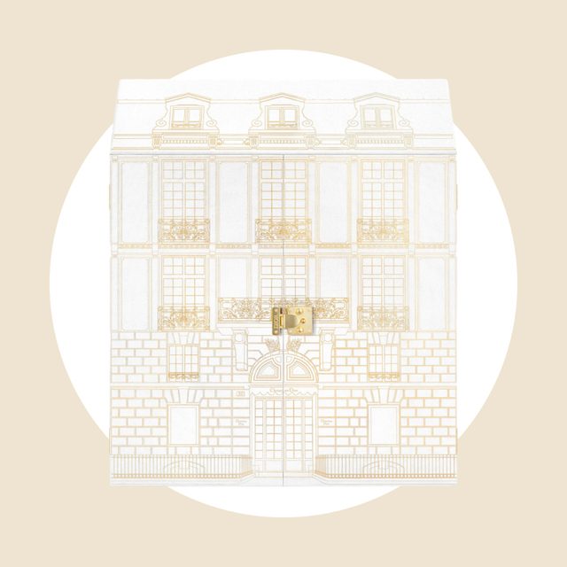 Building illustration adorns box; gold closure centered; minimalistic style on beige background.
