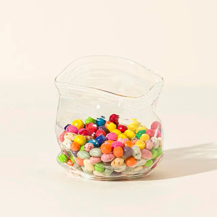 Glass jar holding colorful candies, sitting on a light-colored surface.