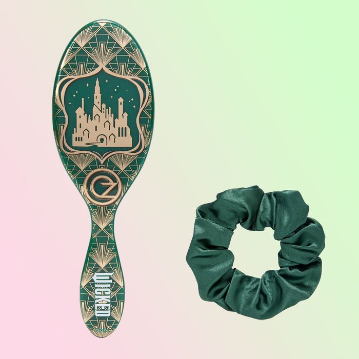 Brush featuring a city silhouette rests beside a green scrunchie, set against a soft gradient background. Text: 