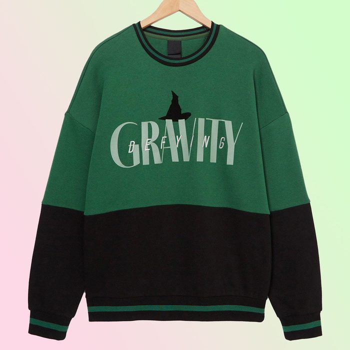 Sweater hangs on a wooden hanger, displaying the text 