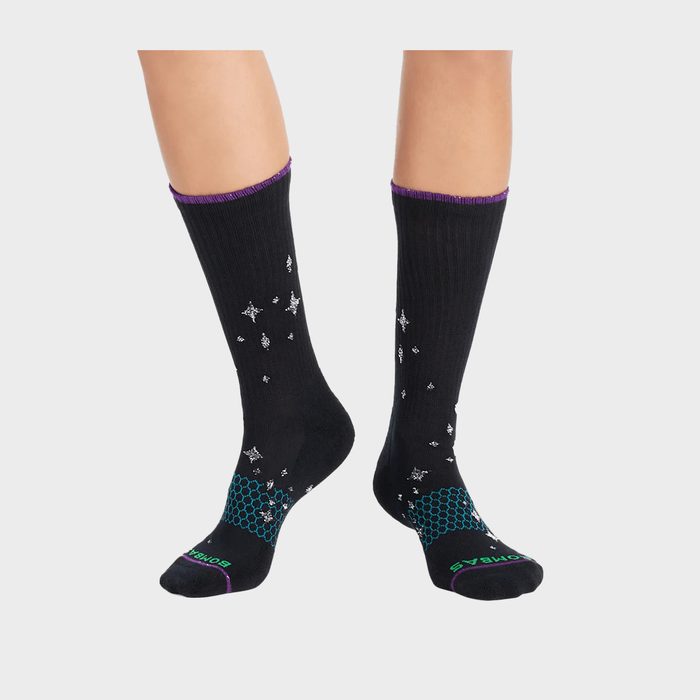 Black socks featuring star patterns, worn on feet, against a plain light background. Text on socks reads 