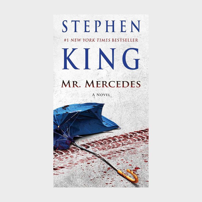 An overturned blue umbrella lies beside bloody tire tracks on a concrete surface; text reads 