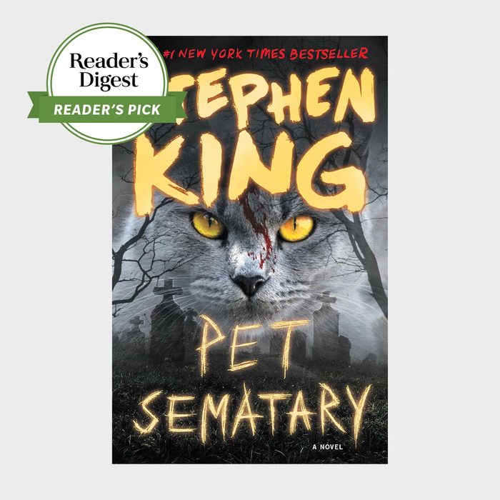 A cat with glowing yellow eyes and a blood-streaked face overlooks a graveyard, framed by Stephen King's name; 