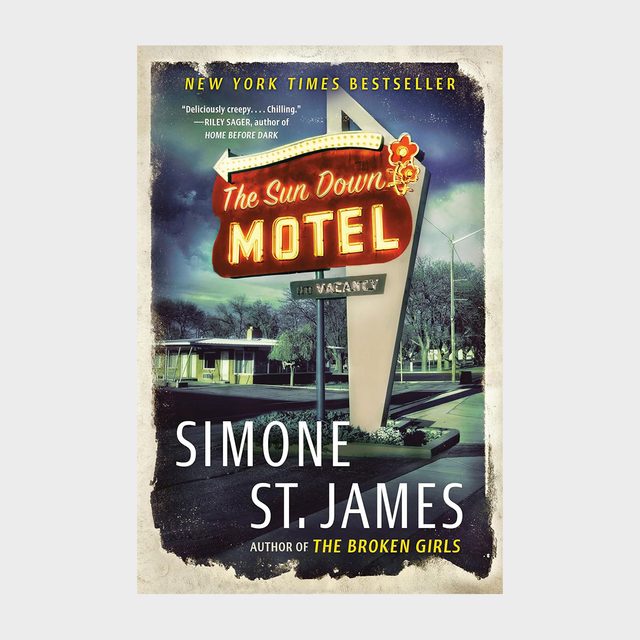 A vintage neon motel sign glows at night, surrounded by trees and buildings. Text: 