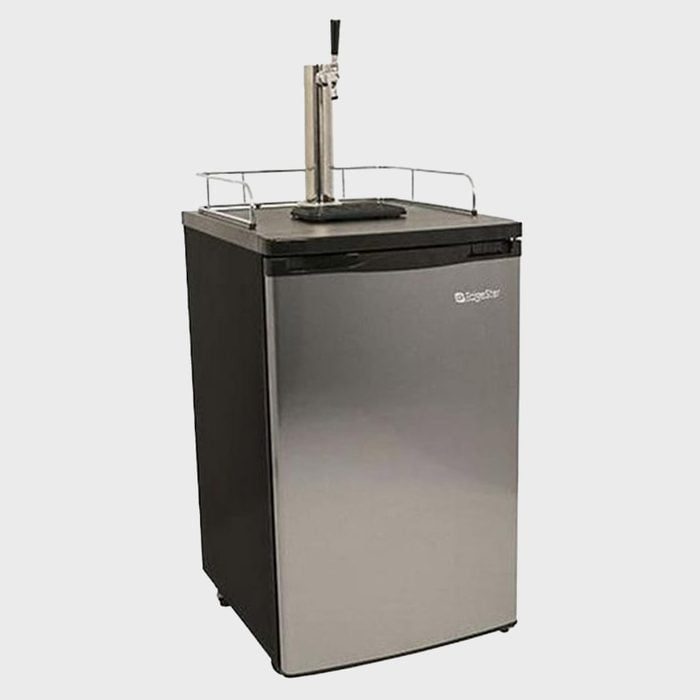 Kegerator dispenses beverages through a tap on top, surrounded by a metal railing, placed in a plain setting.