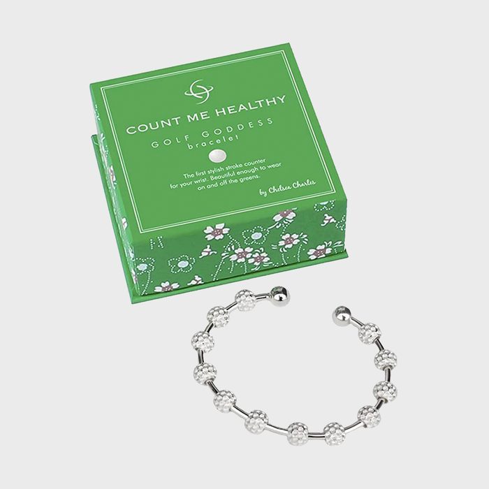 Bracelet lies open near green box with floral design, displaying text: 