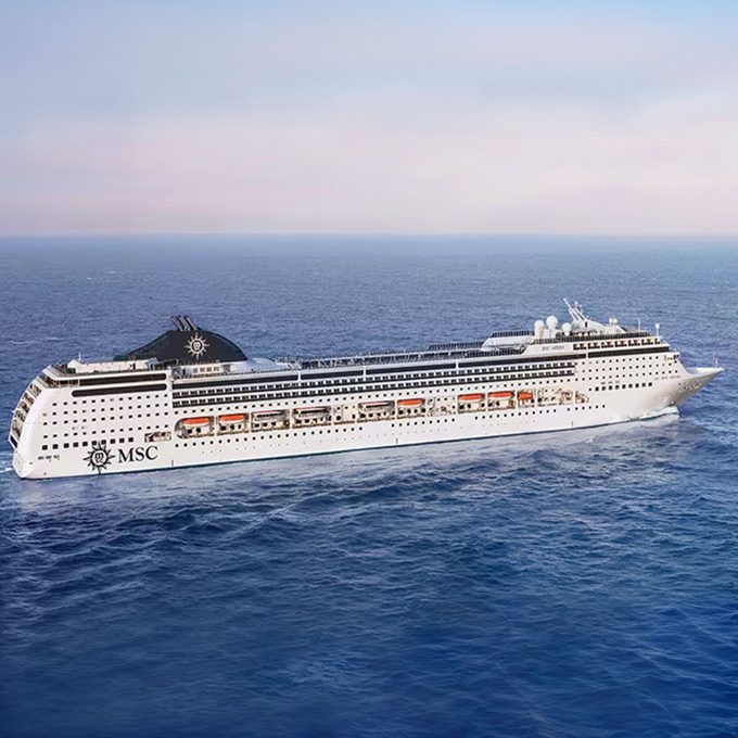 Cruise ship sails through the open ocean, with clear sky and calm water, labeled 