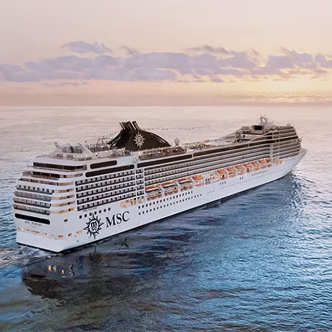 Cruise ship sails on calm ocean during a sunset, branded MSC on the side.