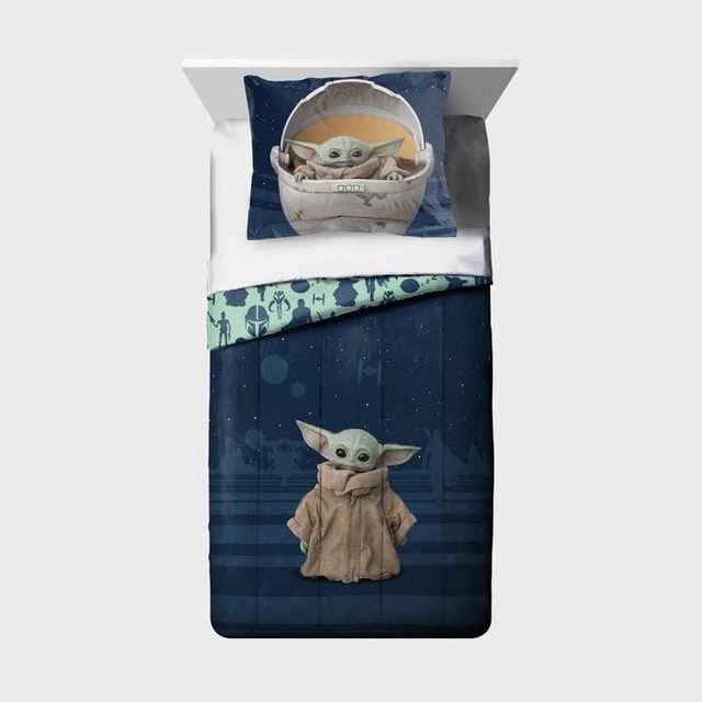 Bedding set features cartoon character with large ears, printed on pillow and blanket, amidst starry space-themed patterns and silhouettes of various figures.