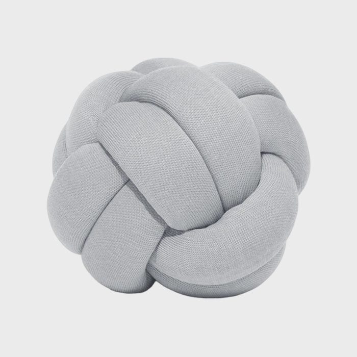 A grey, soft knot pillow resting against a plain white background.