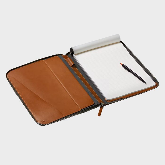 Zippered leather portfolio containing an open notepad with a pen placed on it, situated on a plain light background.