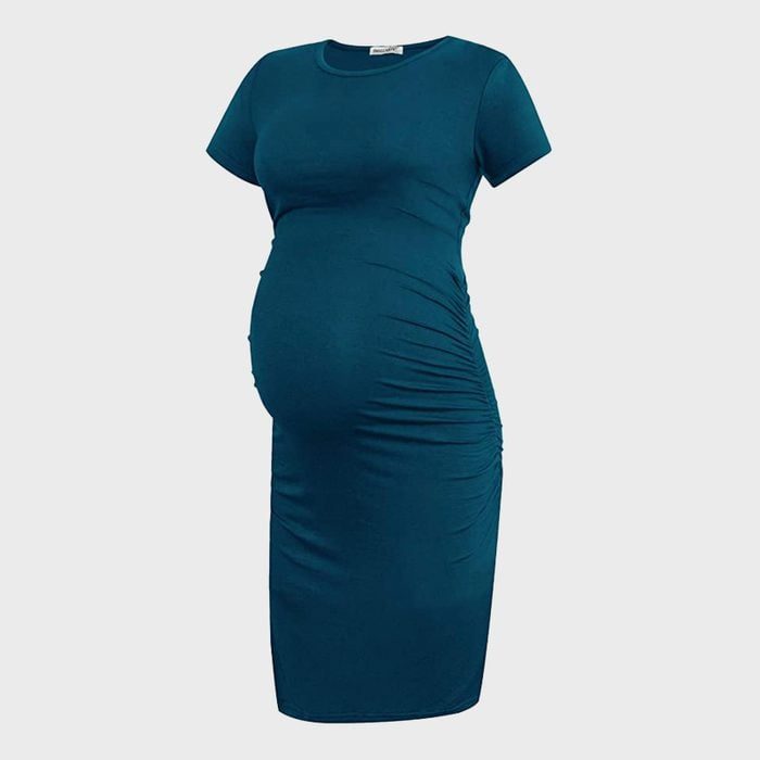 A teal maternity dress is displayed against a plain background, showing its stretchy fabric and ruched sides for comfort and style.