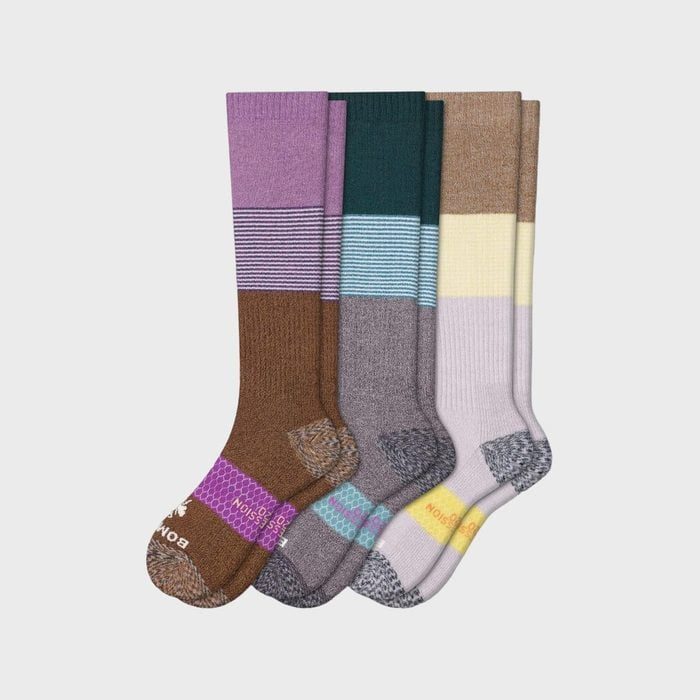 Four pairs of colorful, striped socks are laid flat, showcasing different shades and patterns on a plain background.