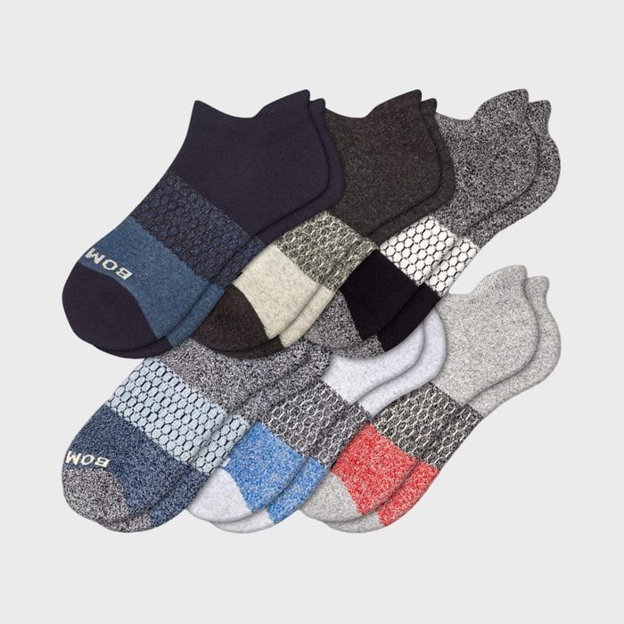 Socks lie stacked, showcasing various colors and patterns, arranged neatly against a plain background. 