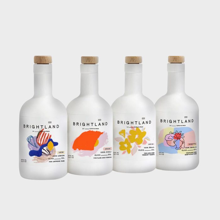 Four white bottles display colorful abstract labels and wooden corks, standing against a plain background. Text reads 