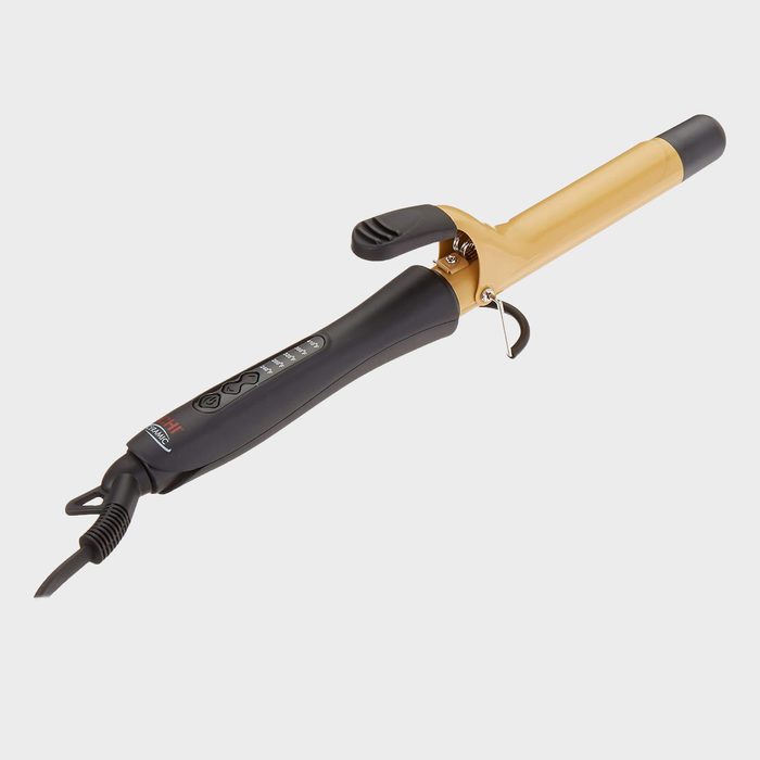 A curling iron rests against a plain white background, featuring a black handle and a gold heating barrel with a clamp.