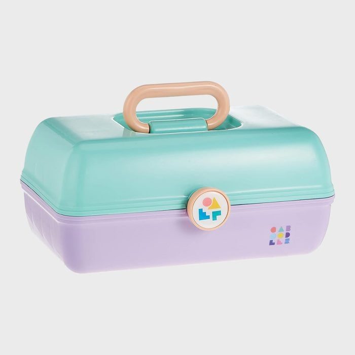 A mint green and lavender plastic lunchbox with a beige handle rests on a white background. Two small geometric logos are present.