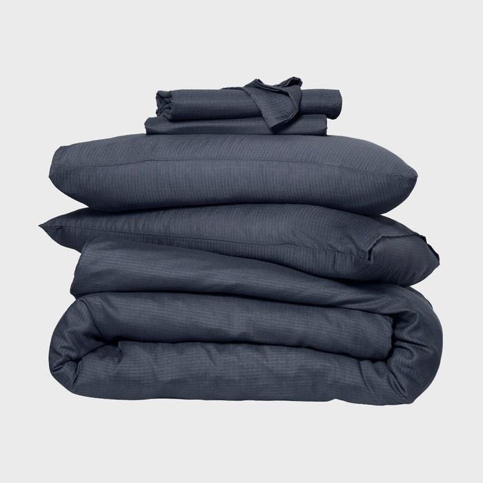 Bedding set lies neatly stacked; includes a comforter, pillow, and sheet in dark gray, against a plain light gray background.