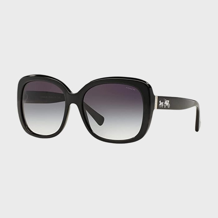 Sunglasses rest, showcasing black square frames with gradient lenses; a small logo embellishes the temple, set against a plain light gray background.
