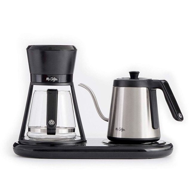Coffee maker sits on a black base, featuring a clear glass pot and metallic gooseneck kettle labeled 