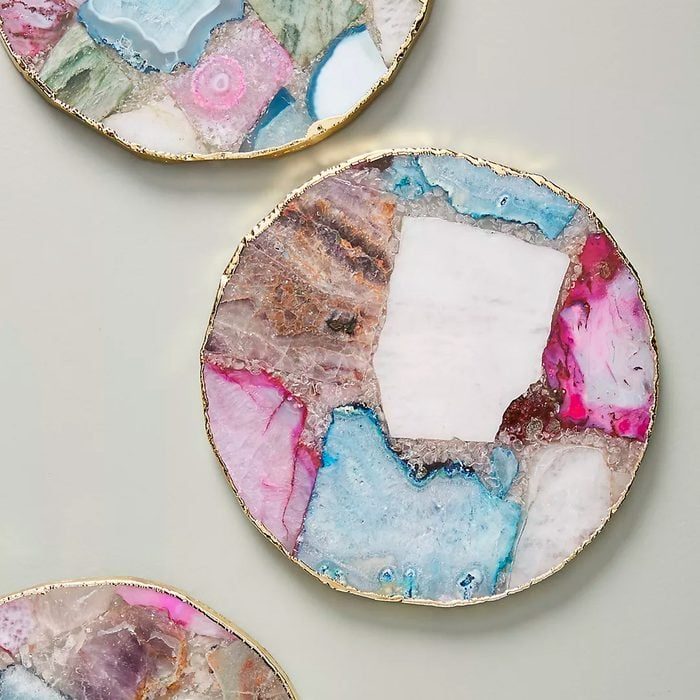 Coasters display colorful, abstract patterns with gold edges, arranged on a flat, neutral surface.