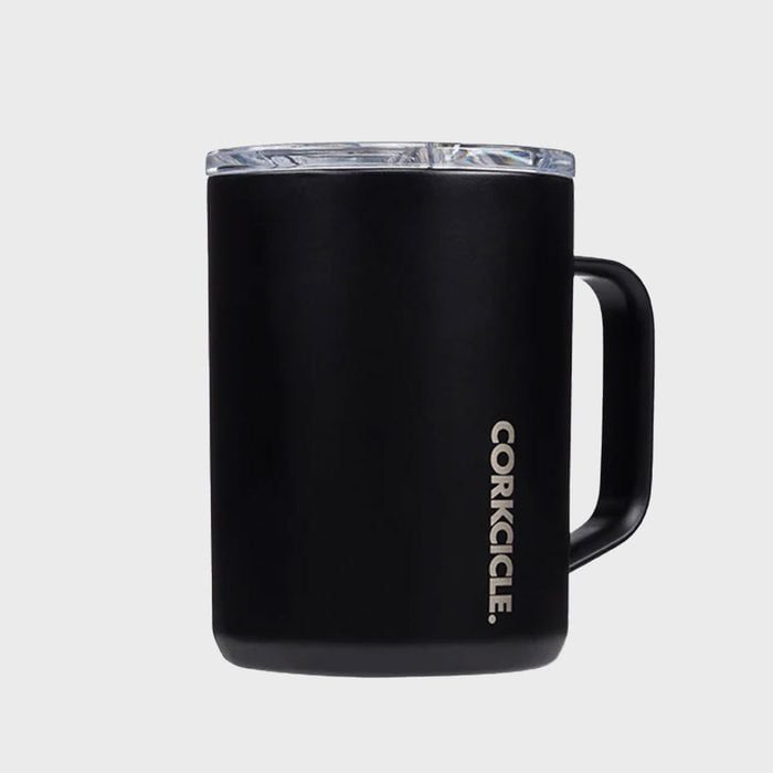 Black mug with a handle is standing against a gray background. Text 