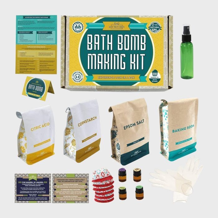 Kit components arranged, displaying bath bomb ingredients and tools. Includes labeled bags, bottles, gloves in a home crafting context.