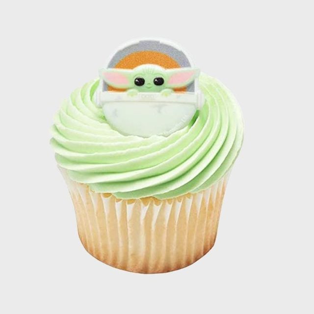 Cupcake topped with green frosting, featuring a decorative Baby Yoda figure, set against a plain white background.