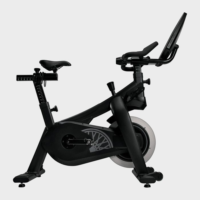 Exercise bike positioned sideways, featuring adjustable seat and handlebars, integrated screen for interactive workouts, against a plain white background.