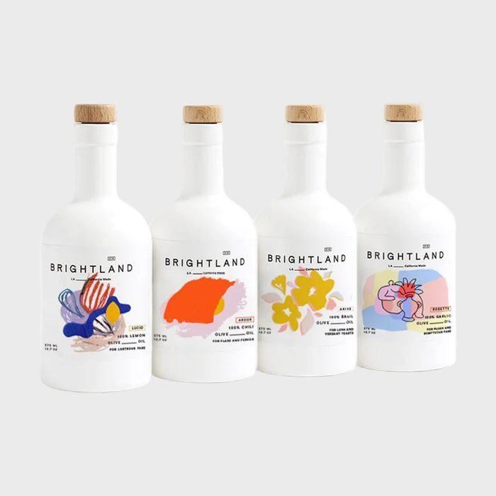 Four white bottles display colorful abstract designs, standing side by side on a light background. Labels read 